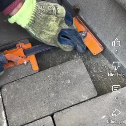 HARAZIN Michał Harazin - Precyzyjne układanie szarej kostki brukowej przy krawężniku z użyciem narzędzi, rękawice robocze w kadrze. Detal pracy brukarskiej.