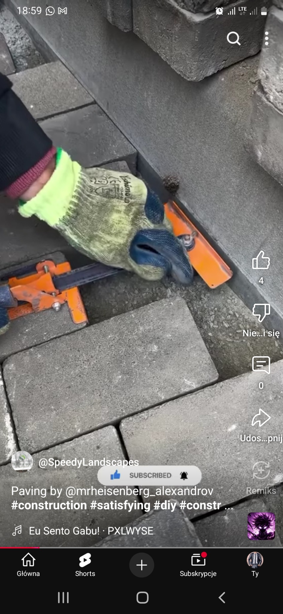 Precyzyjne układanie szarej kostki brukowej przy krawężniku z użyciem narzędzi, rękawice robocze w kadrze. Detal pracy brukarskiej.