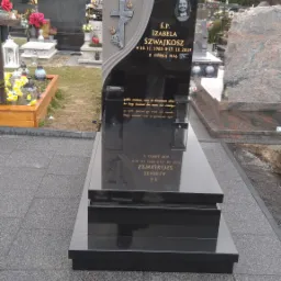 Czarny, nowoczesny nagrobek z szarą wstawką, krzyżem z różami i portretem uśmiechniętej kobiety, otoczony zniczami i kwiatami na cmentarzu z widokiem na góry.