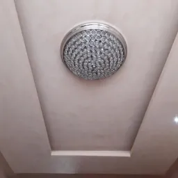 Wykończony sufit z gładzią, dekoracyjną wnęką i okrągłą lampą sufitową z kryształkami, widok z dołu.