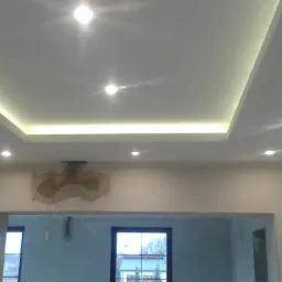 Nowoczesny sufit podwieszany z oświetleniem LED, widoczne przygotowania do wykończenia ściany z ubytkiem tynku.