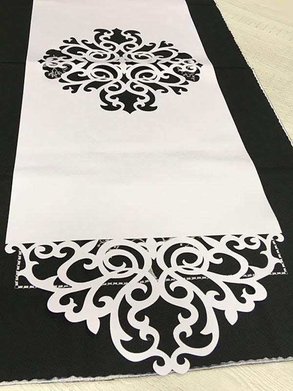 Biały bieżnik z ażurowym wzorem leżący na czarnym materiale, prezentujący precyzyjne wycięcia.