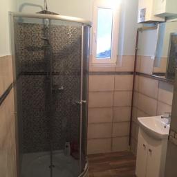 Pach-Bud - Ukończona łazienka z kabiną prysznicową z mozaiką, umywalką z szafką, grzejnikiem oraz oknem