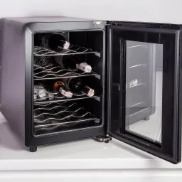 Czarna, wolnostojąca chłodziarka do wina z otwartymi drzwiami, ukazująca metalowe półki i butelki wina wewnątrz, ustawiona na białym blacie.