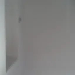 Fragment pomalowanej na biało ściany w rogu pomieszczenia, widoczna mała niedoskonałość w postaci ciemniejszego punktu.