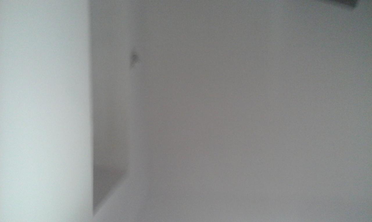 Fragment pomalowanej na biało ściany w rogu pomieszczenia, widoczna mała niedoskonałość w postaci ciemniejszego punktu.