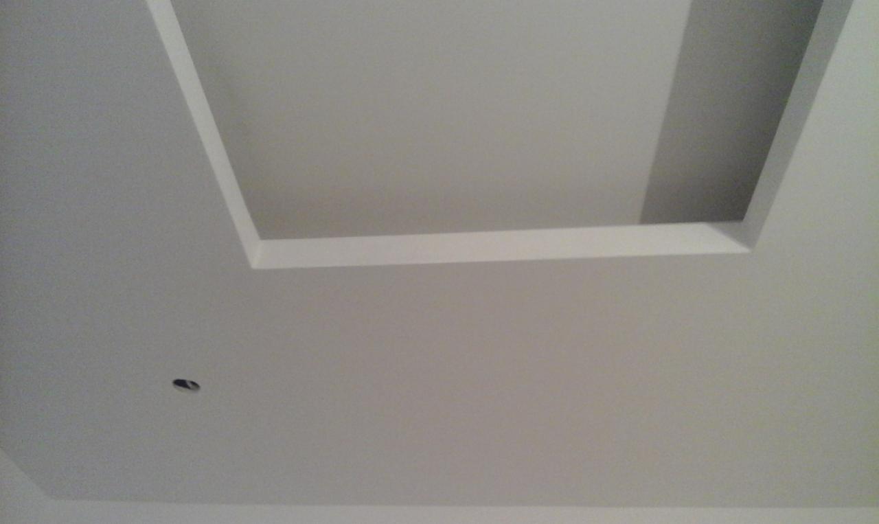 Wykończony sufit z wnęką oświetleniową w kształcie prostokąta, z widocznym otworem na punktowe oświetlenie w dolnej części kadru.