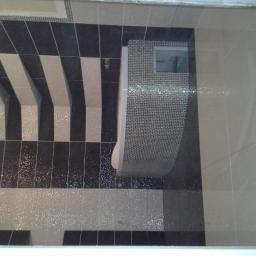 stylren - Wykończona łazienka z oryginalnym wzorem czarno-białych pasów na podłodze i ścianie, oraz mozaiką wokół toalety.