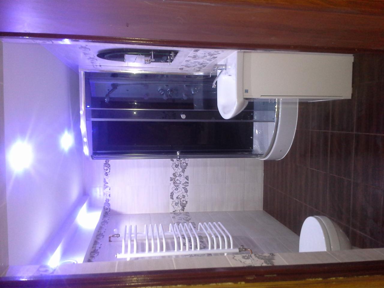 Nowoczesna łazienka z kabiną prysznicową z czarnymi drzwiami, umywalką nablatową i grzejnikiem drabinkowym na tle jasnych i ciemnych płytek z dekoracyjnym wzorem.