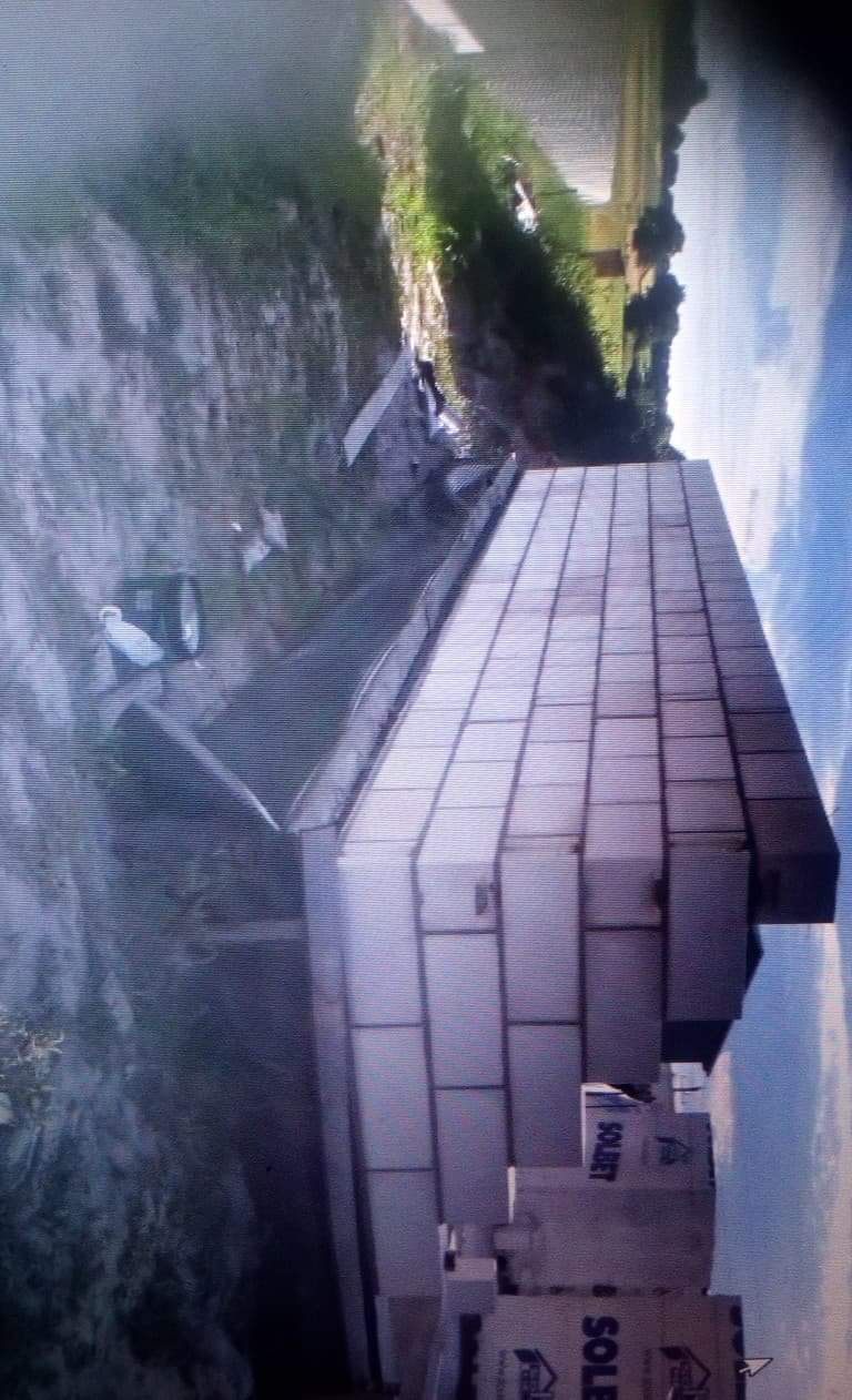 Ściana fundamentowa w trakcie budowy z widocznymi bloczkami betonowymi, częściowo zasypana ziemią, z widocznymi opakowaniami bloczków i fragmentem krajobrazu w tle.