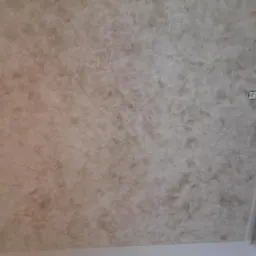 Beżowa, dekoracyjna faktura na suficie w rogu pokoju, widoczna puszka instalacyjna i niedoskonałości wykończenia.