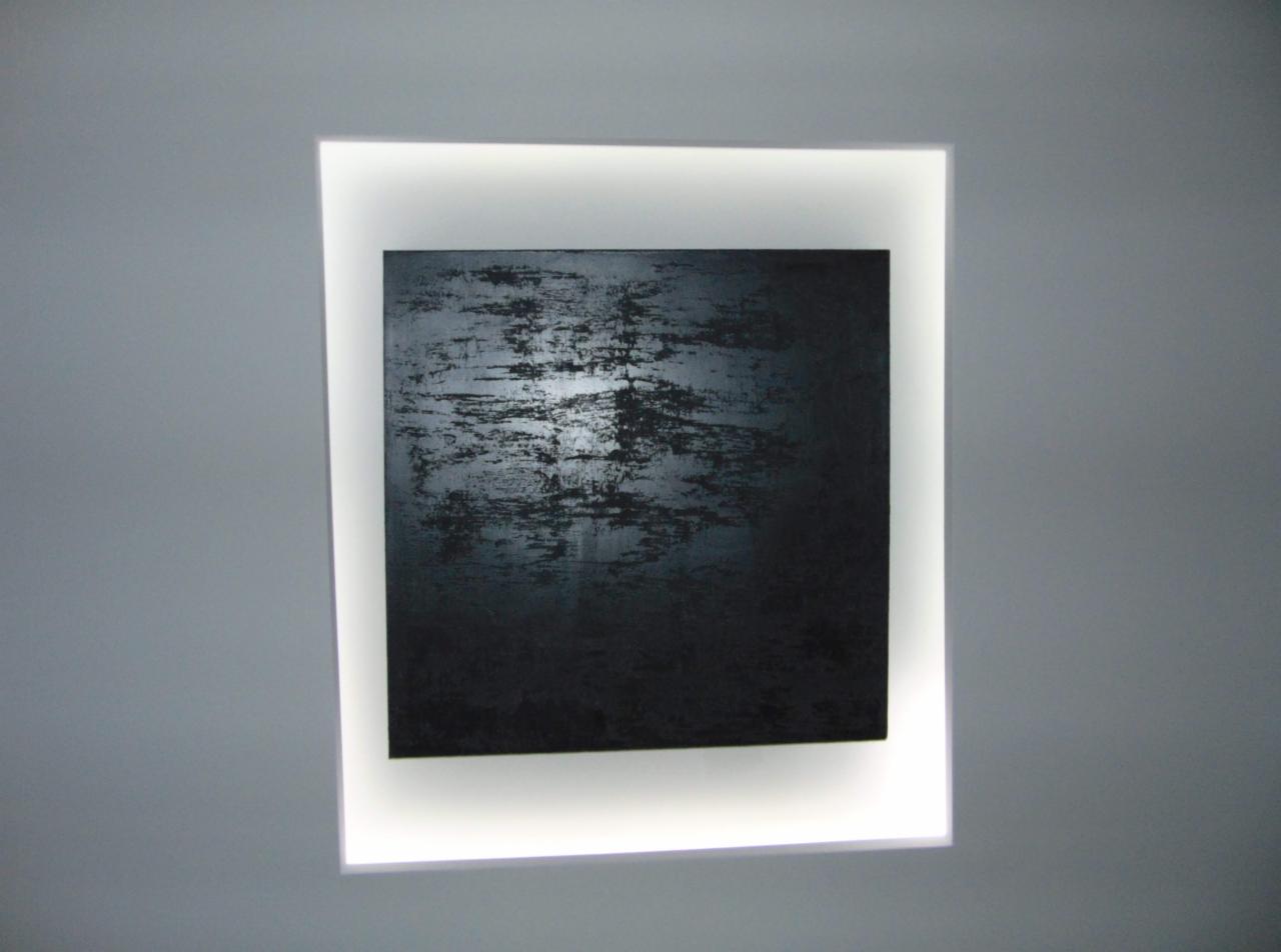 Wnęka ścienna z podświetleniem LED eksponująca abstrakcyjny obraz w odcieniach czerni i szarości.