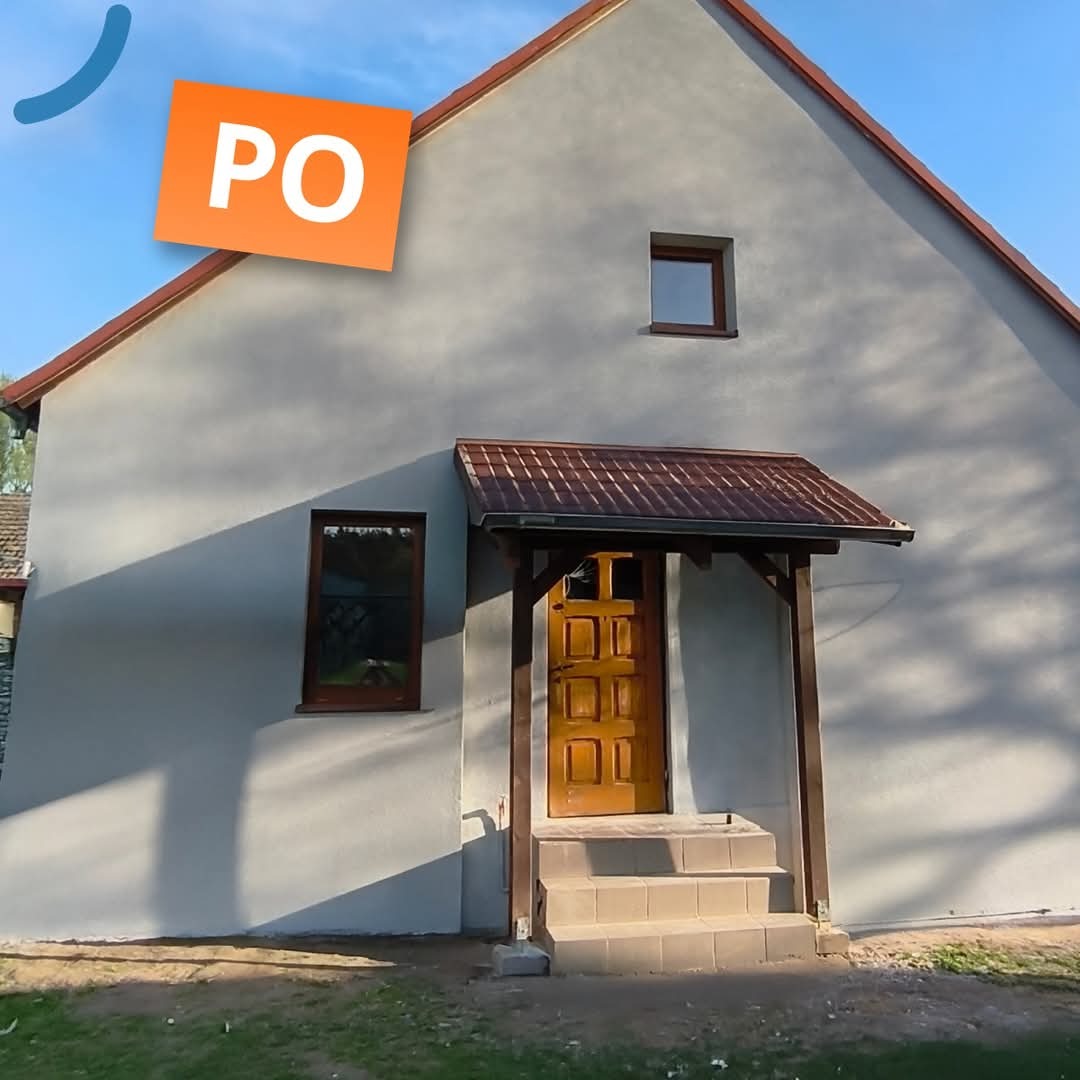 Elewacja domu po remoncie, z nową strukturą i ociepleniem, widoczne okna i drewniane zadaszenie nad wejściem. Nałożony znak wodny 'PO'.