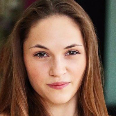 Portret młodej kobiety o brązowych włosach i oczach, z delikatnym makijażem, skierowanej w stronę aparatu.