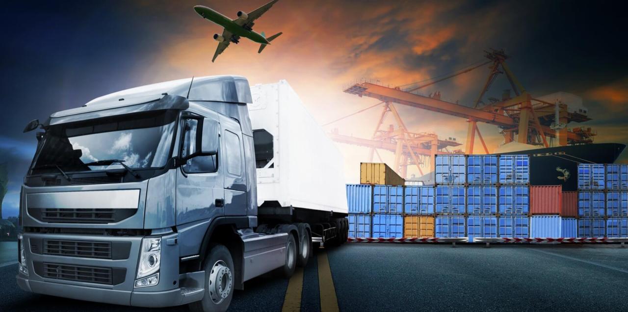 Ciężarówka transportowa z naczepą na tle kontenerów, statku i samolotu na tle zachodzącego słońca.