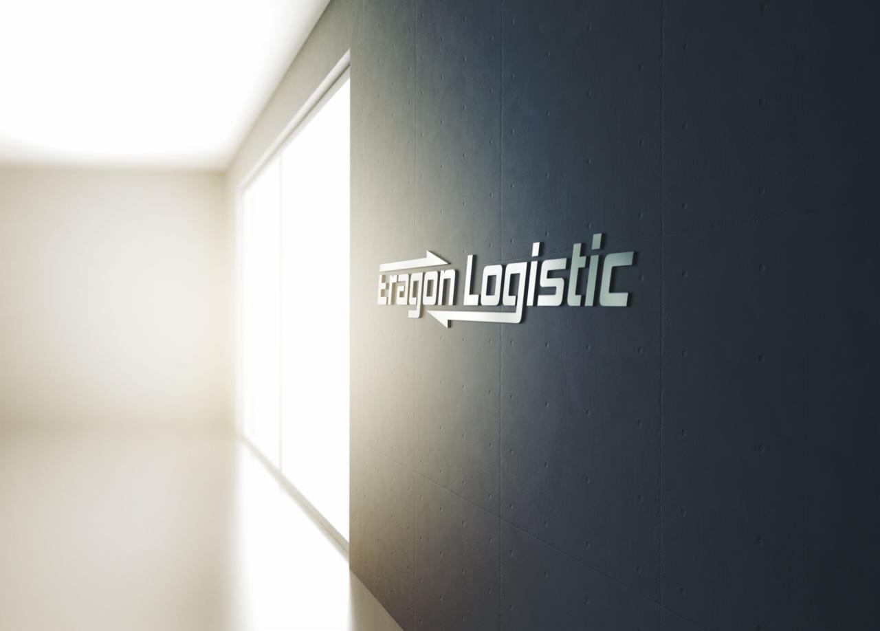 Logo firmy transportowej Aragon Logistic na ciemnoszarej, betonowej ścianie w jasnym korytarzu z oknem.