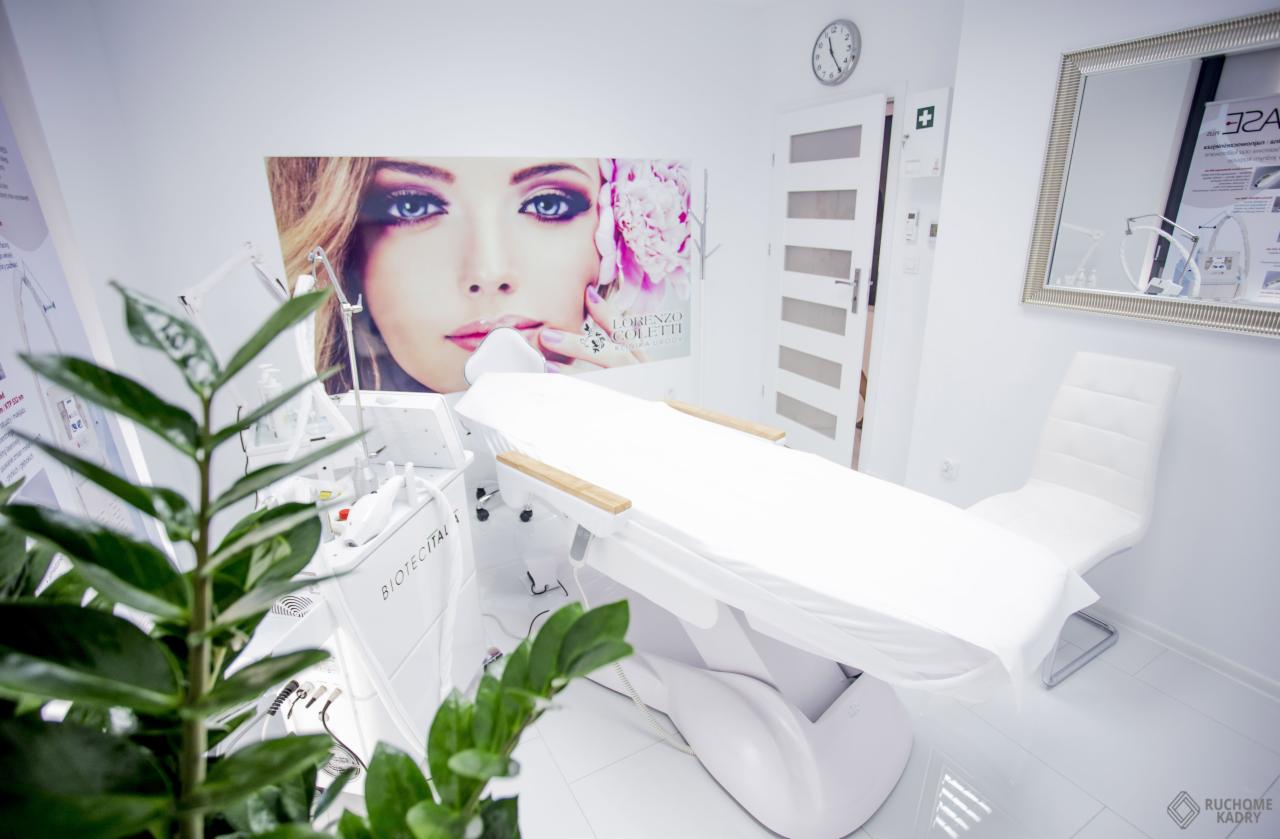 Jasne wnętrze gabinetu kosmetycznego z fotelem do zabiegów, urządzeniem Biotec Italia i plakatem z wizerunkiem kobiety.