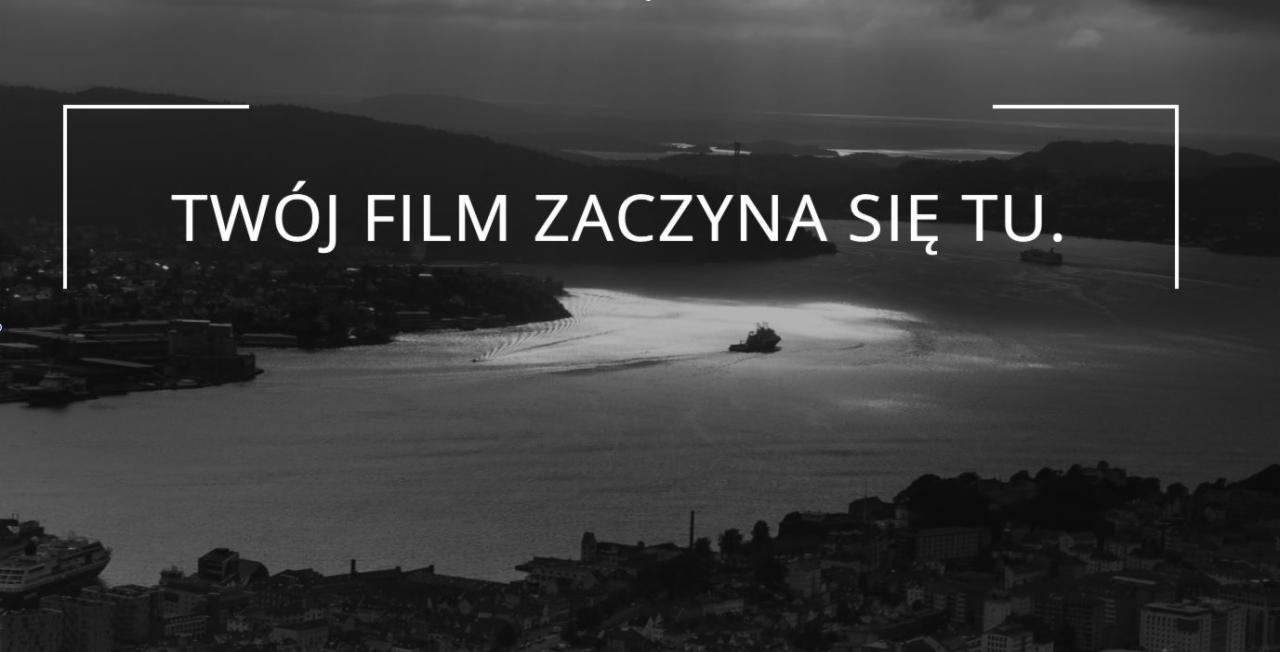 Czarno-biały widok na fiord z budynkami w tle, z napisem 'TWÓJ FILM ZACZYNA SIĘ TU' w białej czcionce.