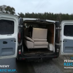 Transport Rzeczy - Wnętrze białego busa z otwartymi drzwiami, w którym znajduje się beżowa sofa gotowa do transportu. Widoczne oznaczenia firmy na tylnej klapie.
