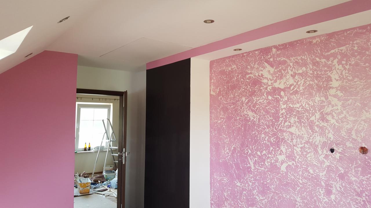 Pokój po odświeżeniu ścian: różowa ściana z efektem dekoracyjnym, widoczna drabina i akcesoria malarskie w tle.