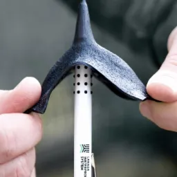 Prezentacja elastycznego elementu uszczelniającego komin dachowy, trzymanego w dłoniach, z widocznym logo 'Canada Waterproof System' na białej rurce z otworami.