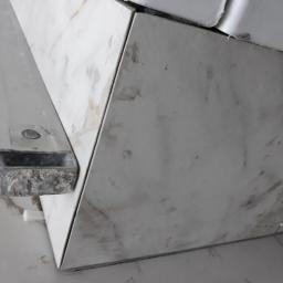 Wood House Group - Fragment narożnika wyłożonego płytkami imitującymi marmur, z widoczną listwą wykończeniową i krzyżykami dystansowymi, wskazujący na etap prac podczas układania płytek.