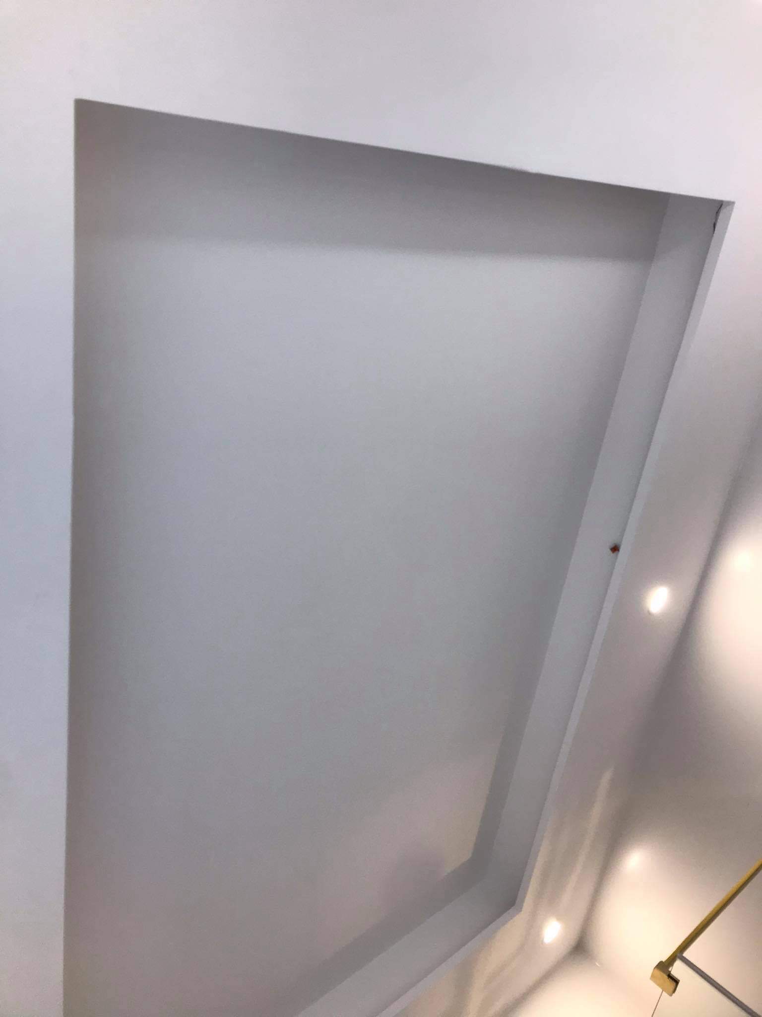 Wykończony sufit z wnęką oświetleniową, pomalowany na biało, widoczny pod kątem od dołu, z delikatnym światłem punktowym.