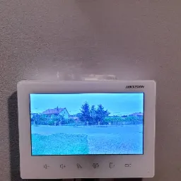 Ekran monitoringu domu Hikvision w Kielcach pokazuje widok z kamery na ulicę i domy w dzień.