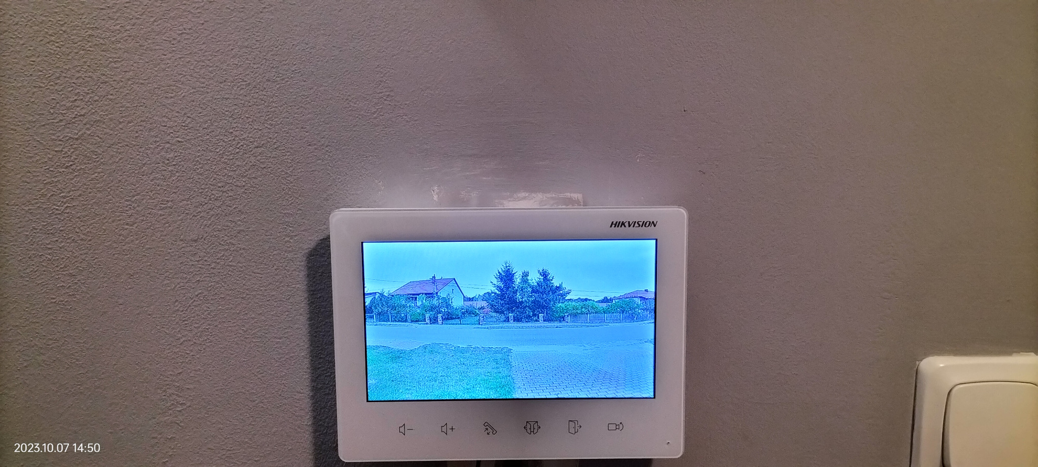Ekran monitoringu domu Hikvision w Kielcach pokazuje widok z kamery na ulicę i domy w dzień.