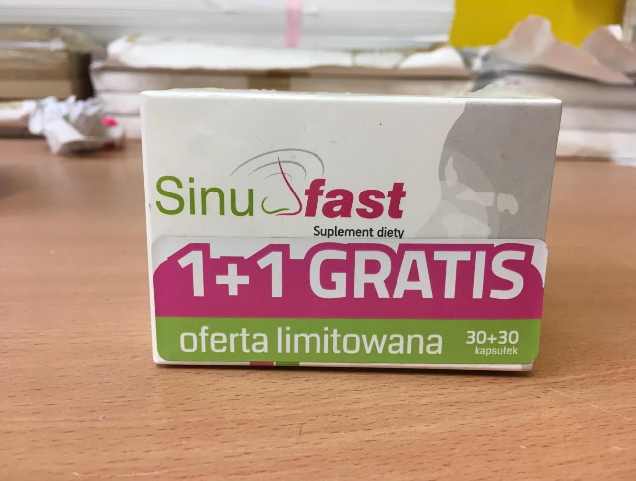 Pudełko suplementu diety SinuFast z napisem '1+1 GRATIS oferta limitowana 30+30 kapsułek' na drewnianym blacie.