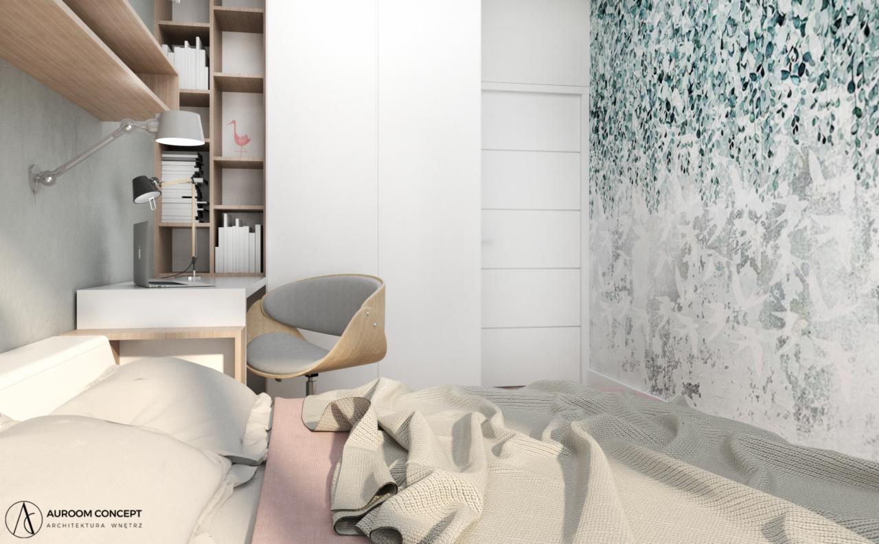 Nowoczesna sypialnia z biurkiem, lampką i tapetą w liście, utrzymana w jasnej kolorystyce, z widocznym łóżkiem z beżową narzutą.