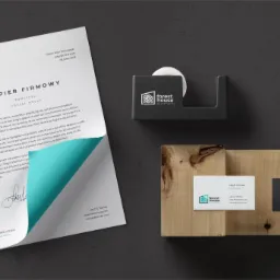 Wizualizacja identyfikacji firmy Forest House: papier firmowy z turkusowym akcentem, wizytówki na drewnianym podkładzie i dyspenser do taśmy z logo, wszystko na ciemnoszarym tle.
