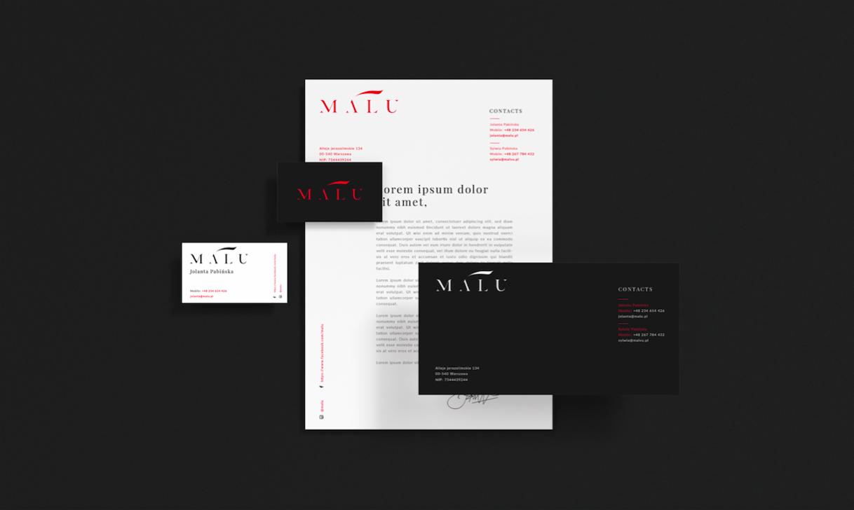 Zestaw materiałów firmowych na ciemnoszarym tle: wizytówki (biała i czarna), papier firmowy z logo i danymi kontaktowymi, minimalistyczny design z elementami w kolorze czerwonym.
