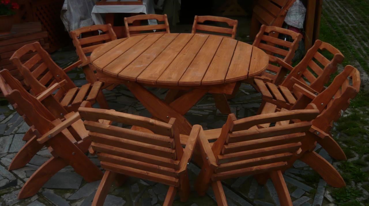 Komplet mebli ogrodowych: okrągły stół i osiem krzeseł z jasnego drewna, ustawione na kamiennej nawierzchni.