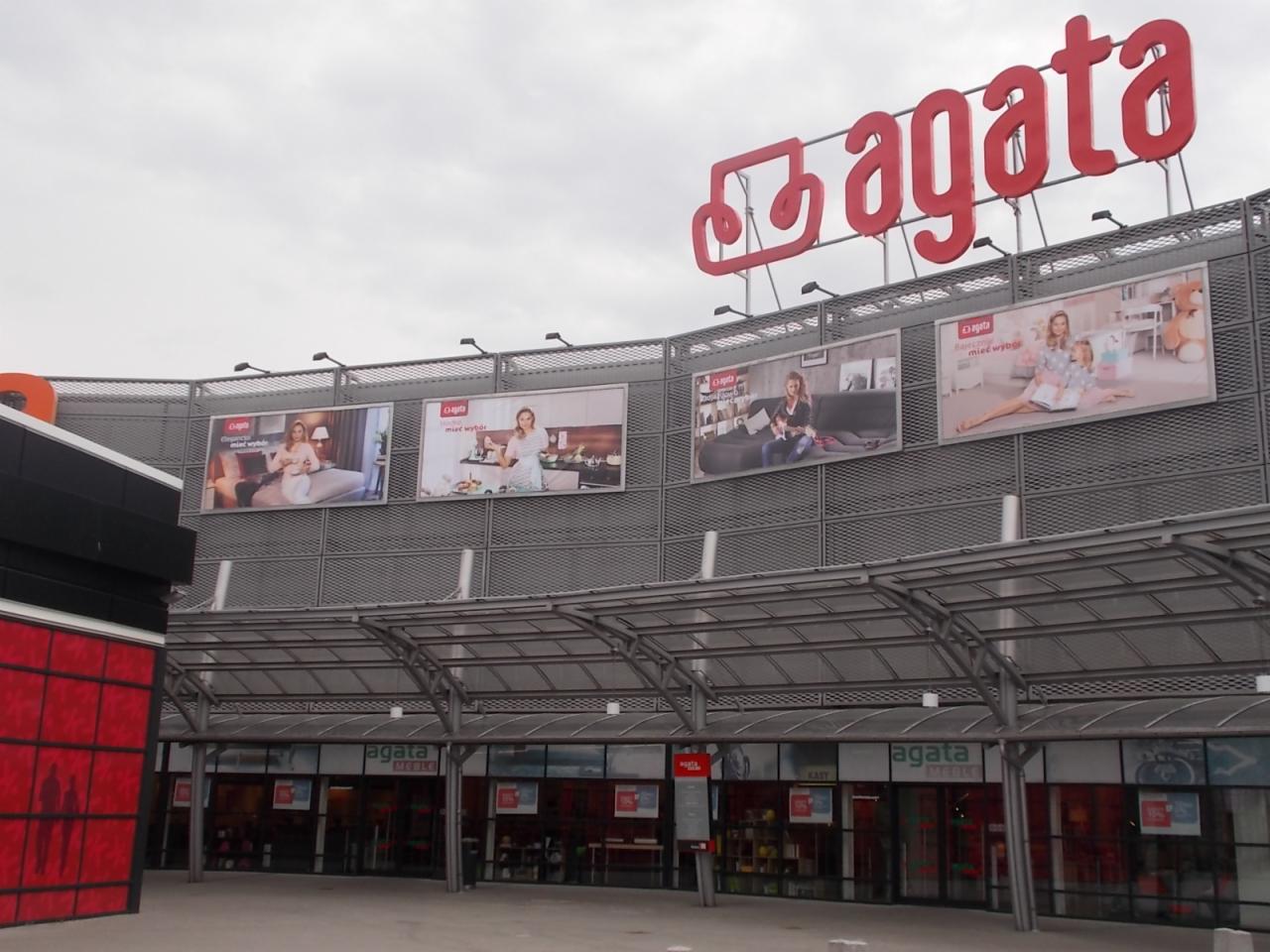 Fasada budynku sklepu meblowego Agata z dużym czerwonym logo i billboardami reklamowymi prezentującymi aranżacje wnętrz.