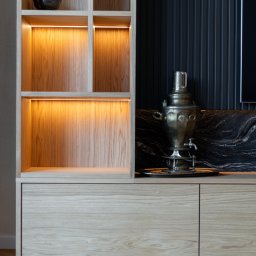 FURSTA Meble Wojciech Ziembla - Drewniana szafka z oświetleniem LED i dekoracyjnym samowarem na blacie z czarnego marmuru. Parkiet w jodełkę na podłodze. Nowoczesny design.