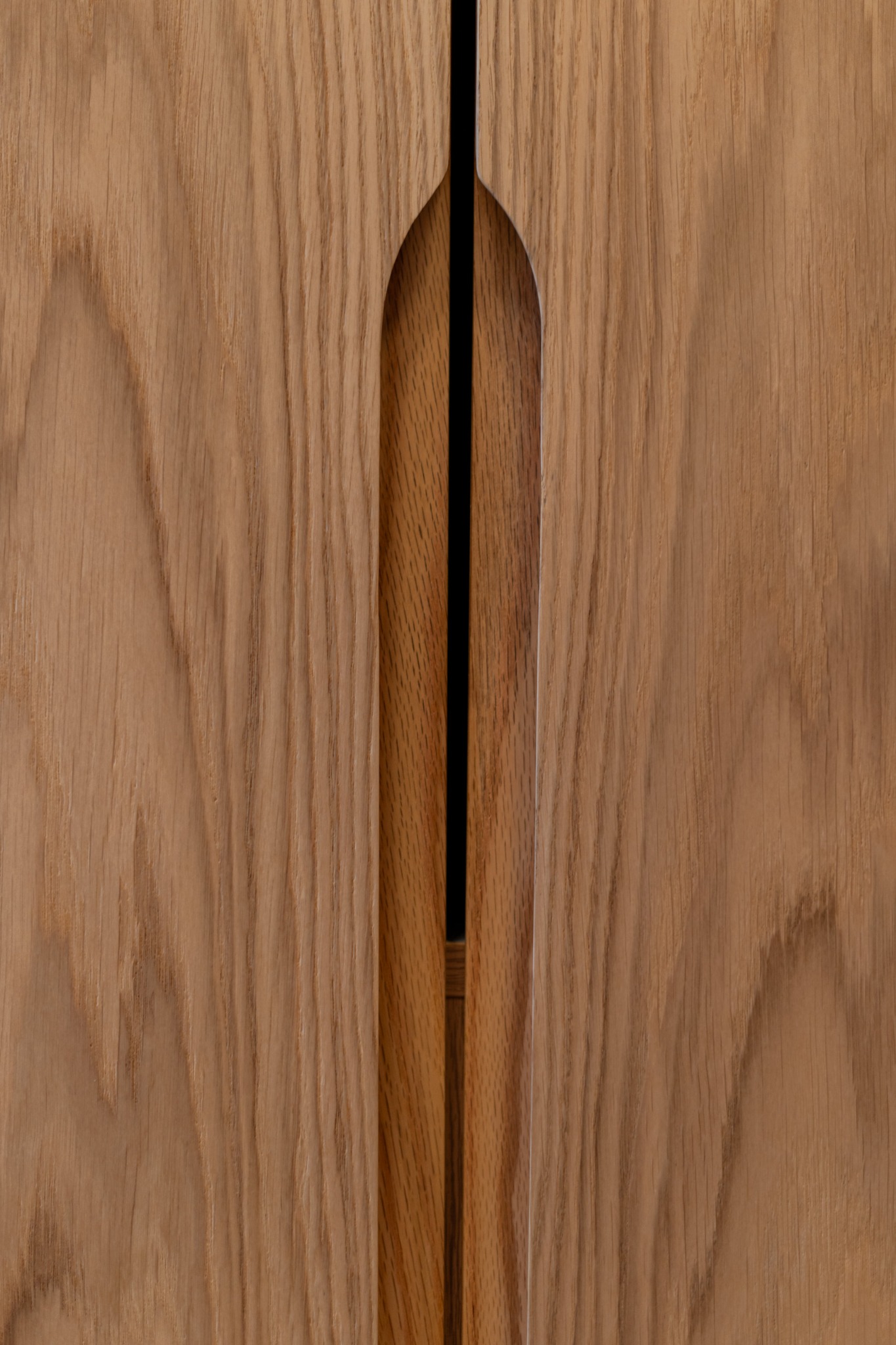 Detal drewnianych frontów szafy z frezowanymi uchwytami, wykonanej na wymiar w Stróży. Naturalny odcień drewna, minimalistyczny design.