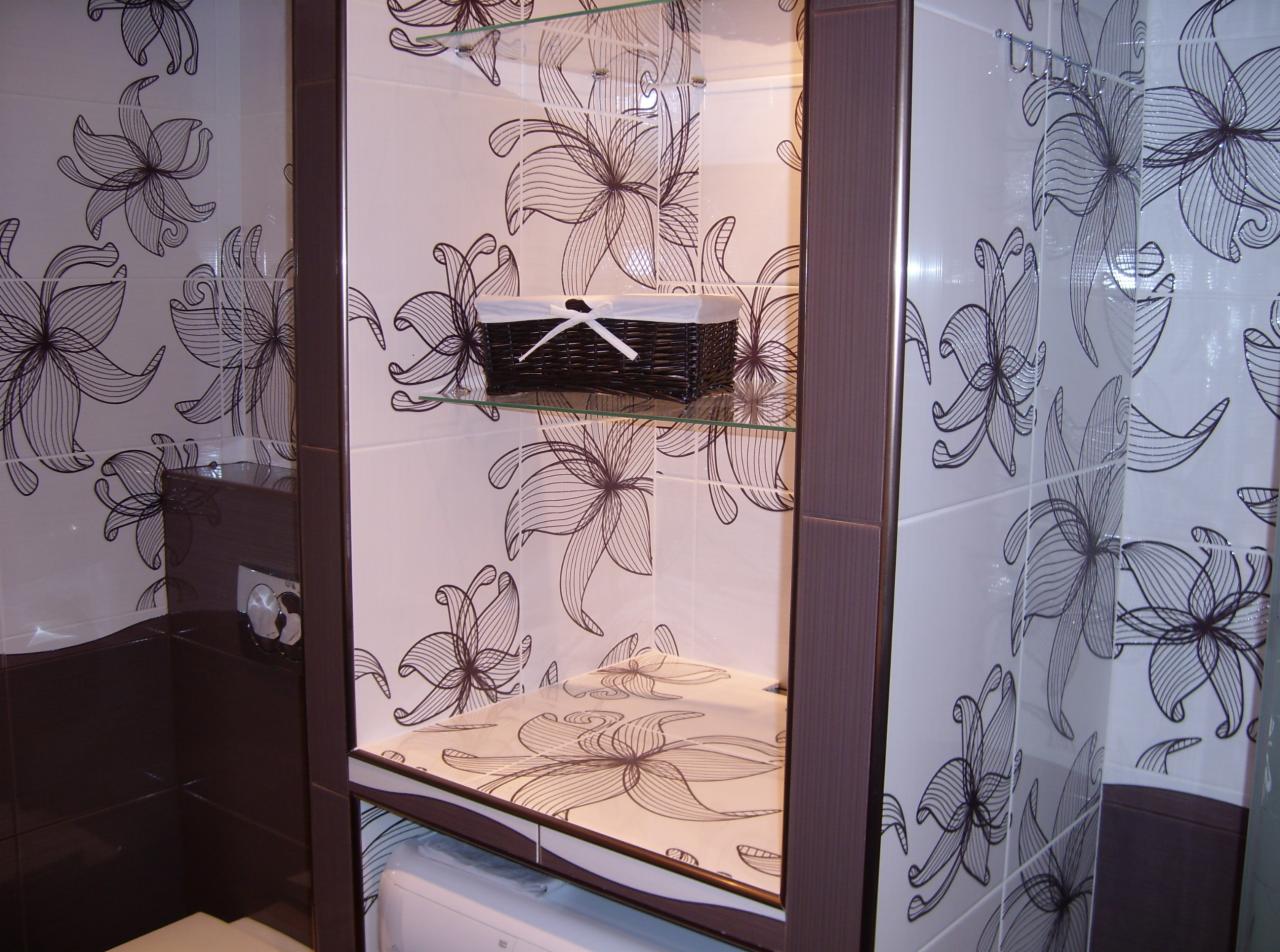 Wykończona łazienka w Pułtusku z brązowo-białymi płytkami w kwiaty, szklane półki w zabudowie i koszyk z białą wstążką.