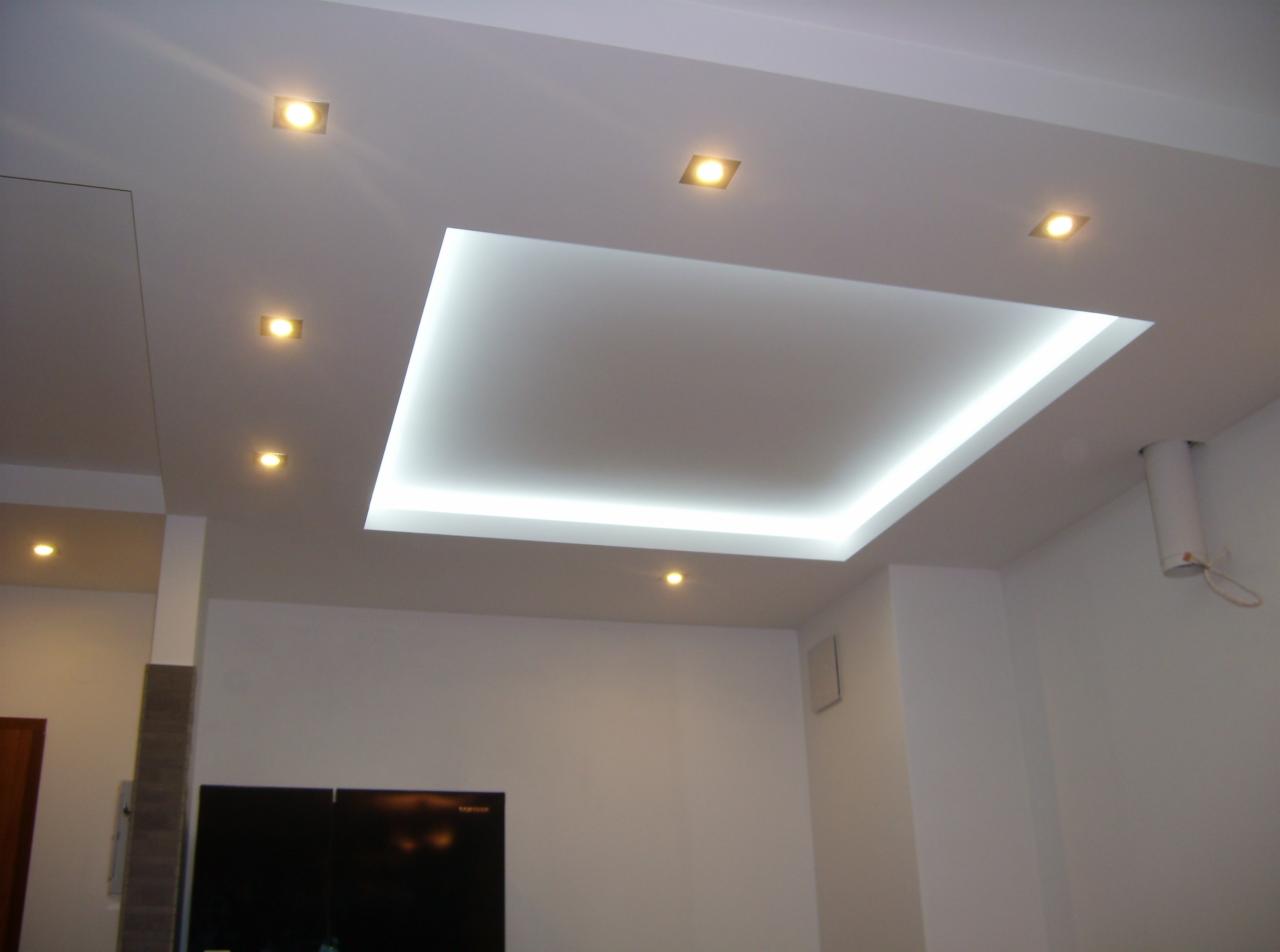 Biały sufit podwieszany z podświetleniem LED i punktowymi lampami halogenowymi w nowoczesnym salonie.