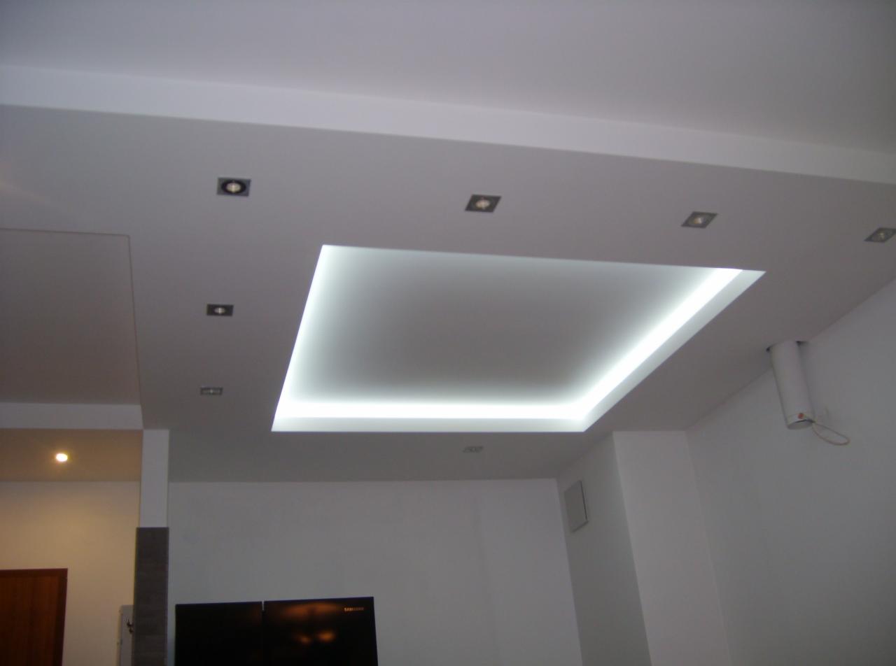 Nowoczesny sufit podwieszany z oświetleniem LED w kształcie kwadratu, uzupełniony punktowymi lampami halogenowymi i białymi ścianami.