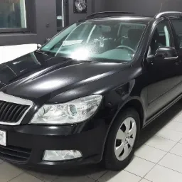 Błyszcząca, czarna Skoda Octavia Combi po umyciu w myjni, widoczny filtr powietrza sprężonego na ścianie w tle.