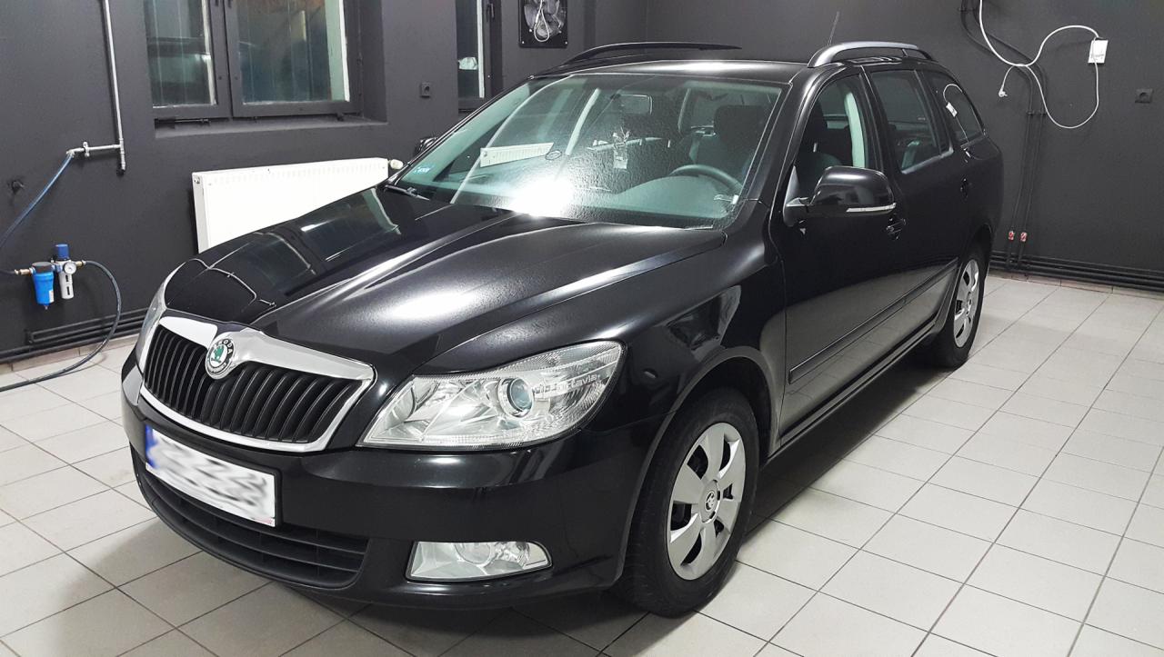 Błyszcząca, czarna Skoda Octavia Combi po umyciu w myjni, widoczny filtr powietrza sprężonego na ścianie w tle.