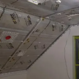 Montaż izolacji termicznej Isover Vario na poddaszu, widoczne profile i folia paroizolacyjna, przygotowanie do montażu płyt kartonowo-gipsowych.