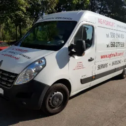 Biały samochód dostawczy Renault Master z reklamą firmy AG Forklift, oferującej serwis, sprzedaż i wynajem wózków widłowych, z numerami telefonów i adresem strony internetowej, zaparkowany...