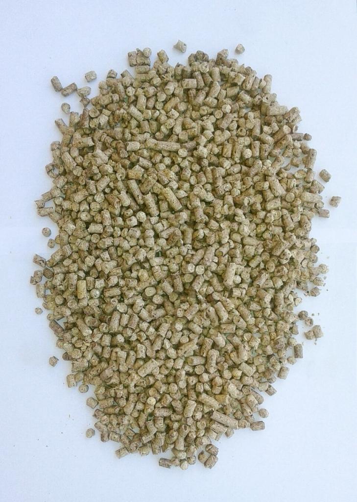 Góra jasnobrązowych, cylindrycznych i kulistych peletów na białym tle, ułożonych nieregularnie.