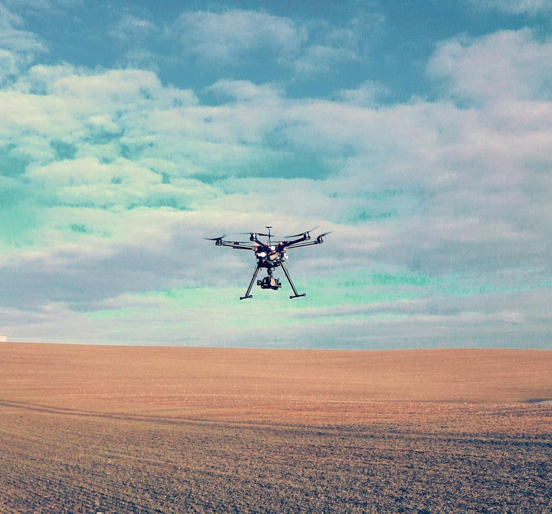 Dron z kamerą w locie nad polem w Krojantach, błękitne niebo z chmurami w tle.