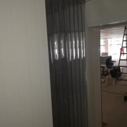 ArkonTech Paulina Kędzia - Przezroczyste, pionowe pasy PCV tworzące kurtynę w wejściu, widoczna osoba pracująca w tle oraz drabina.