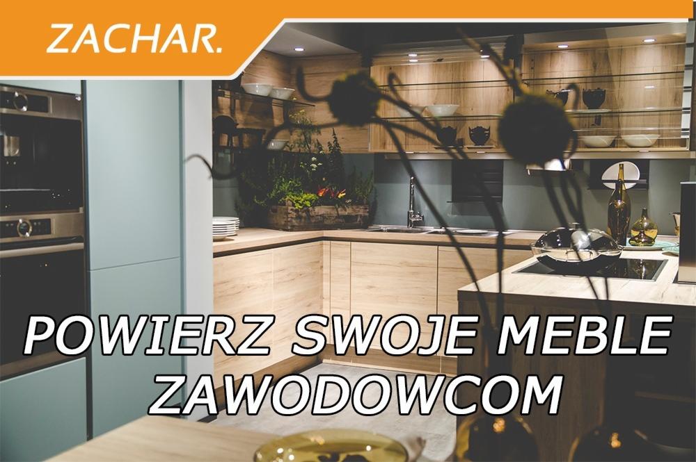 Nowoczesna kuchnia z jasnymi drewnianymi frontami, akcentem roślinnym w drewnianej skrzynce i sprzętem AGD w zabudowie, oświetlona punktowo.