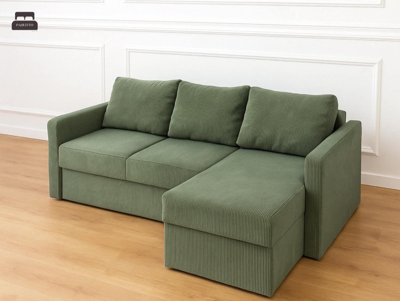 Kordowy narożnik w odcieniach zieleni z trzema poduszkami, ustawiony na drewnianej podłodze, na tle białej ściany z dekoracyjnymi panelami.