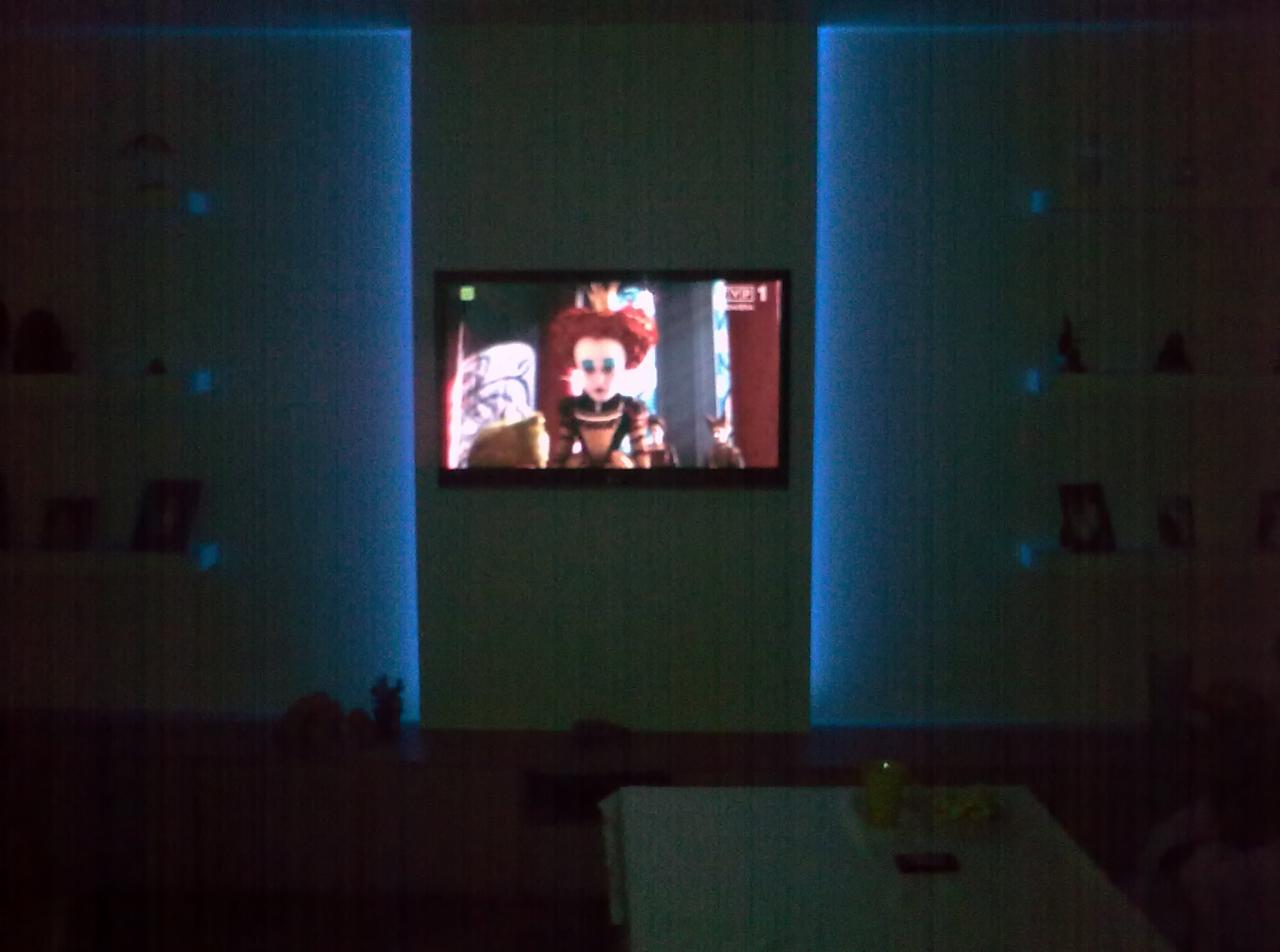 Salon z podświetleniem LED po bokach telewizora, na którym wyświetlana jest animacja